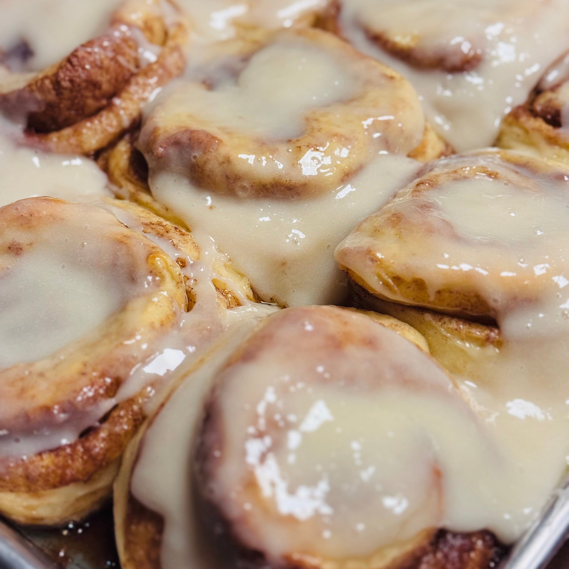 Baked cinnamon rolls with a glaze on a baking tray